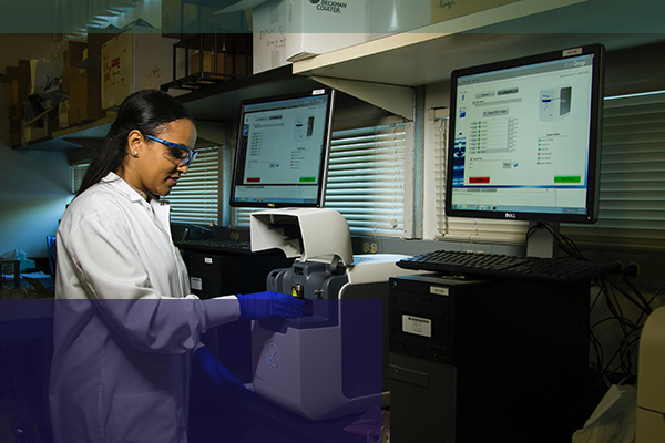 Woman working in lab running tests wearing lab coat and protective glasses TTG in Phoenix, AZ