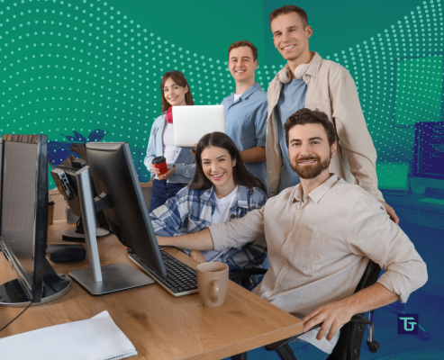 Group of young technical professionals collaborating at computers in a modern office.