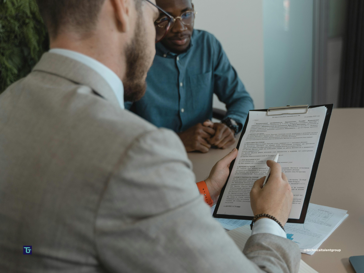 Retained vs contingency search interview with a hiring manager reviewing a candidate’s application on a clipboard.